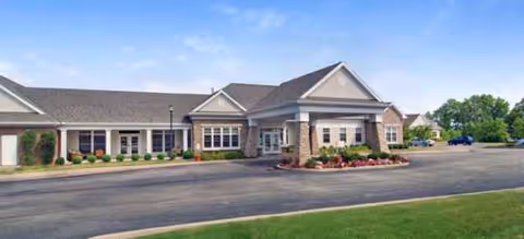 Exterior view of a single-story senior living facility with a driveway and landscaped entrance.