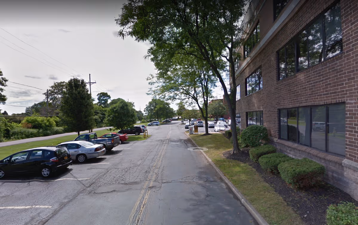 Exterior view of Caring Hearts of Rochester with a brick building and parked cars.