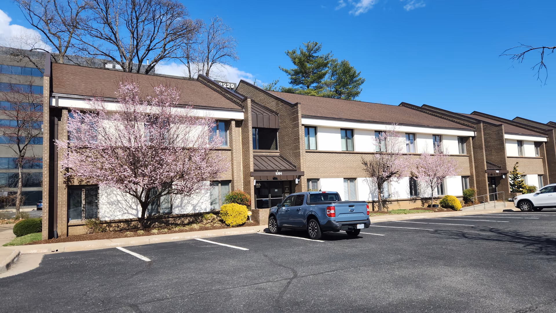 Exterior view of Ata&Ana Home Health Agency facility with parked cars and blooming trees.