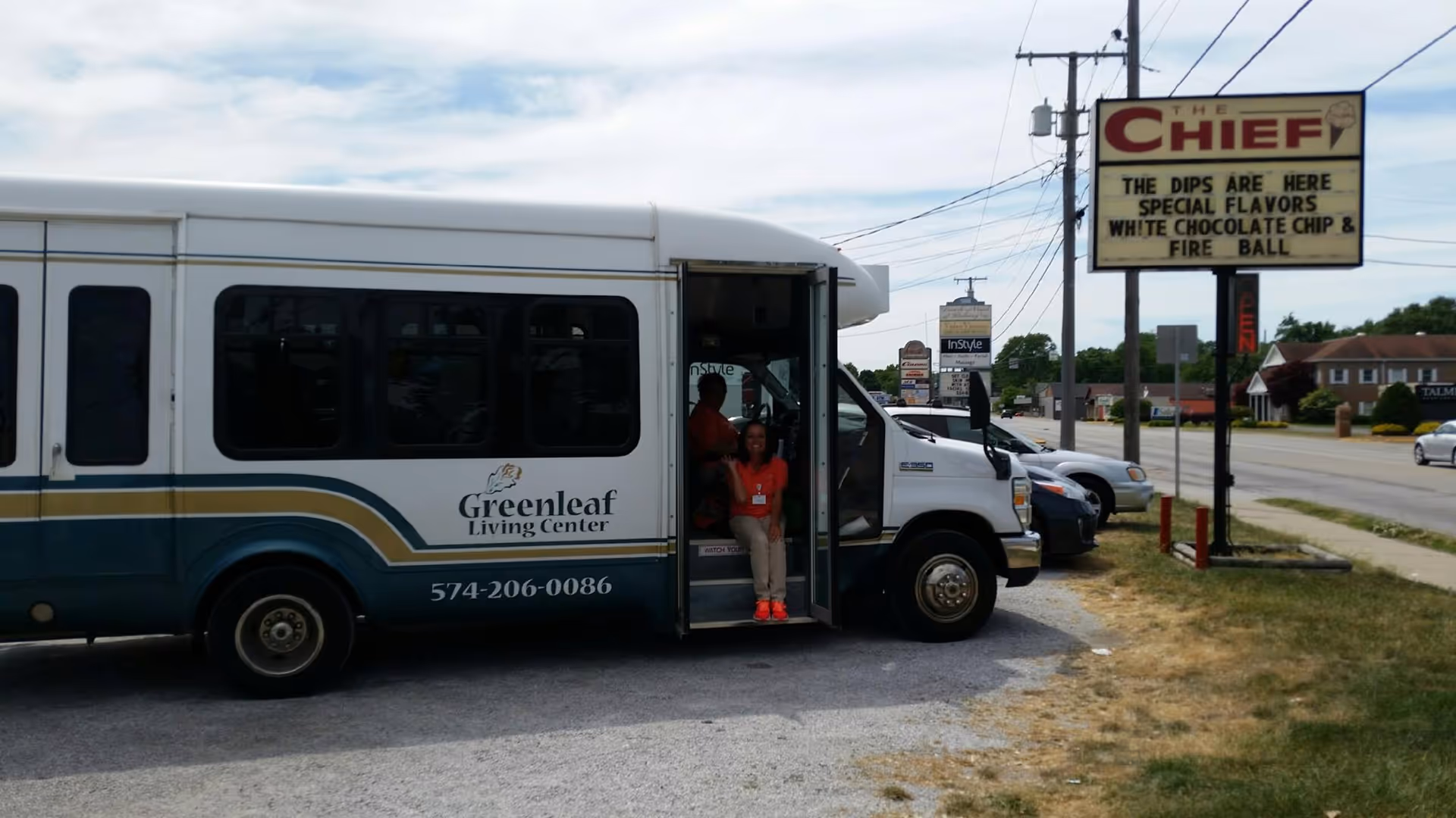 Greenleaf Living Center bus parked by roadside with two people at the door.