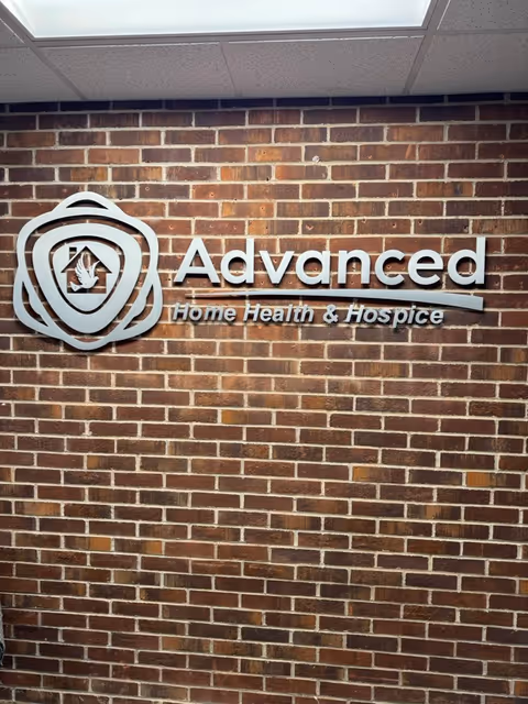 Interior brick wall with a metal sign for Advanced Home Health & Hospice