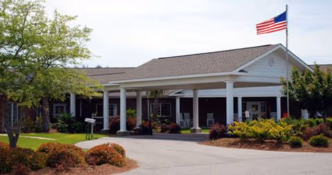 Woodbury Wellness Center exterior with a covered front entry, columns, flag, and landscaped surroundings.