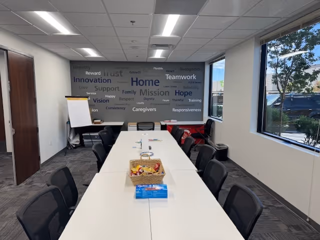 Conference room at Valley Health at Home by BAYADA with tables, chairs, and word cloud wall.