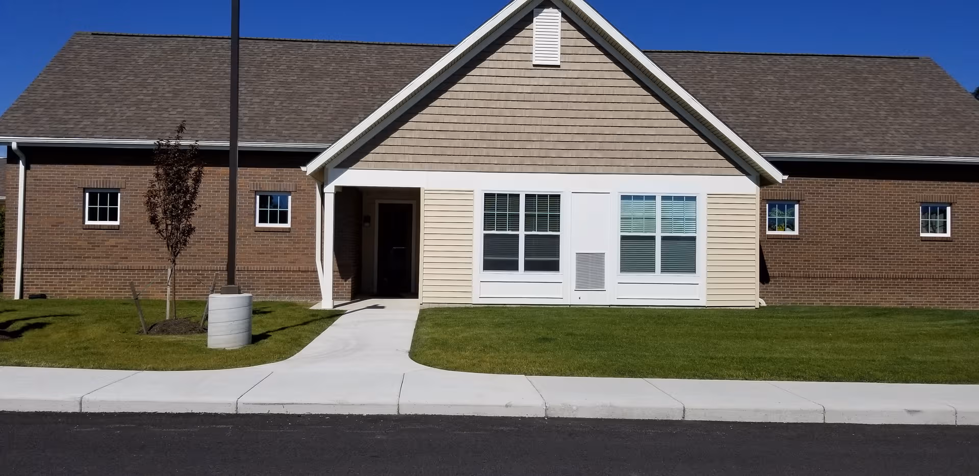 Single-story senior living facility exterior with brick walls, white entrance, and maintained lawn.