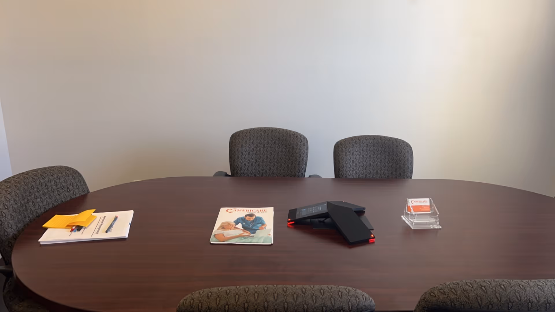Dark wood conference table with papers, a phone, and stacked cards in an empty meeting room.