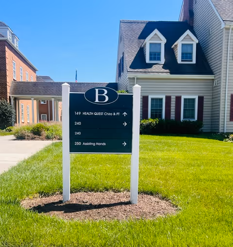 Outdoor sign on a grassy lawn directing to Health Quest and Assisting Hands.