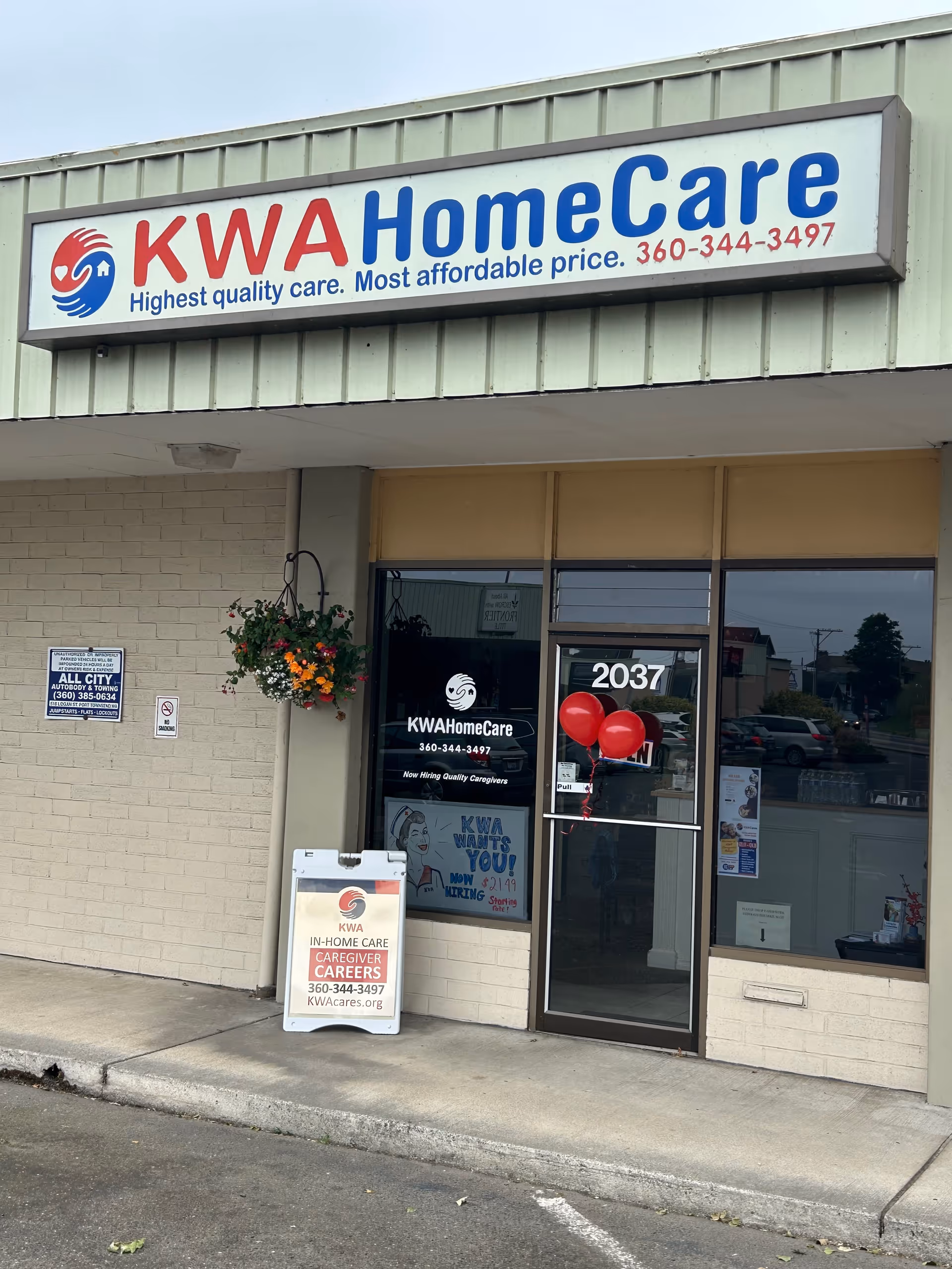 Exterior storefront of KWA HomeCare facility with signage, flowers, and balloons.