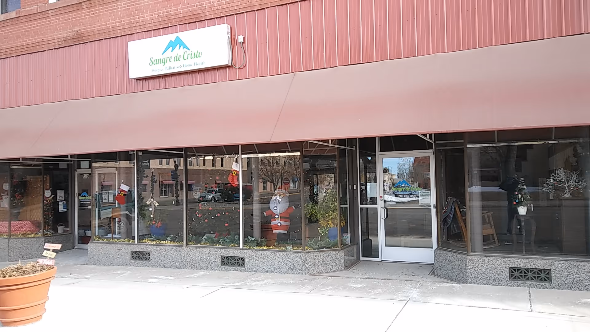 Exterior storefront of Sangre de Cristo Community Care with holiday window decorations.
