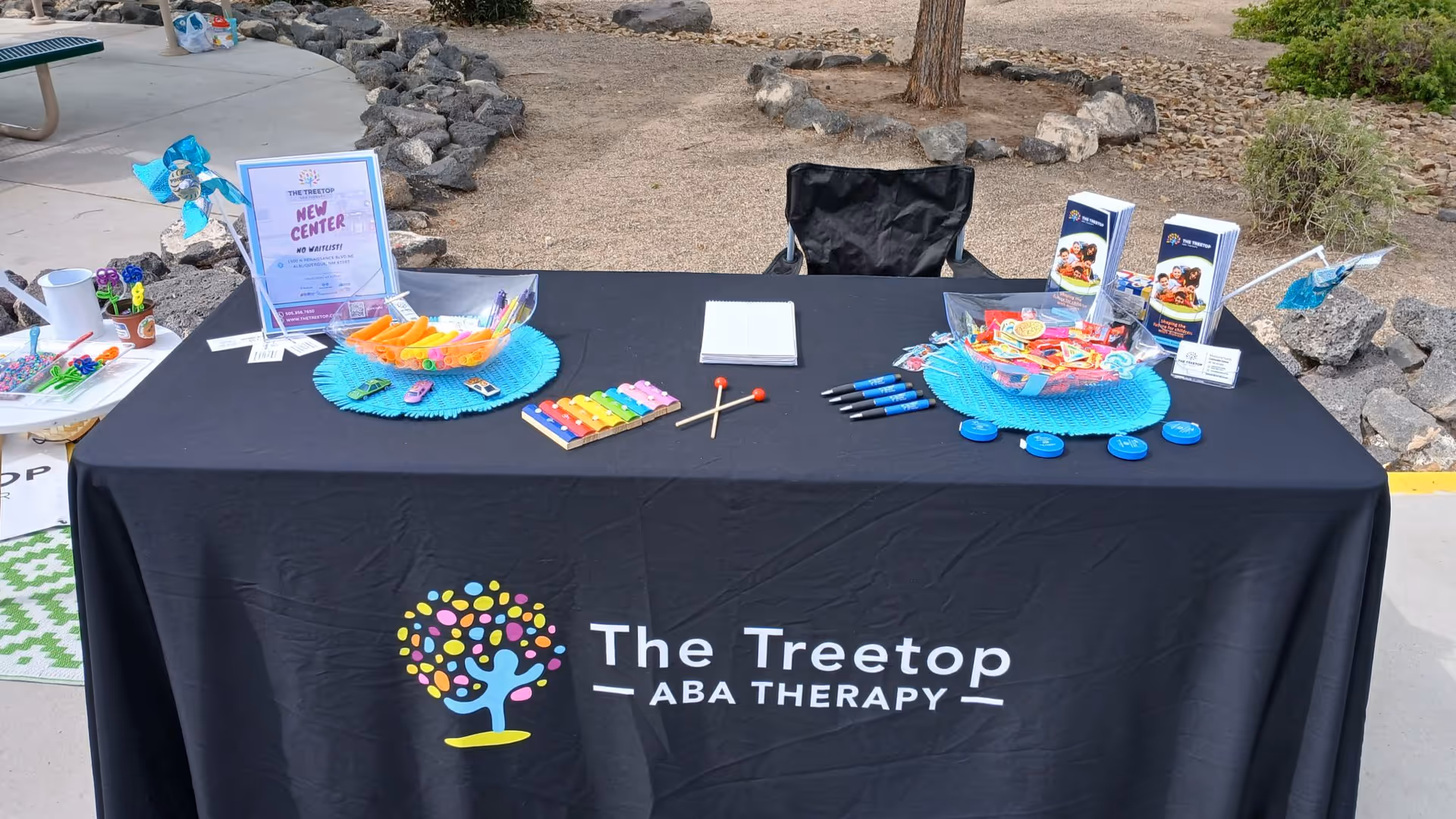 Outdoor promotional table with The Treetop ABA Therapy logo and brochures.