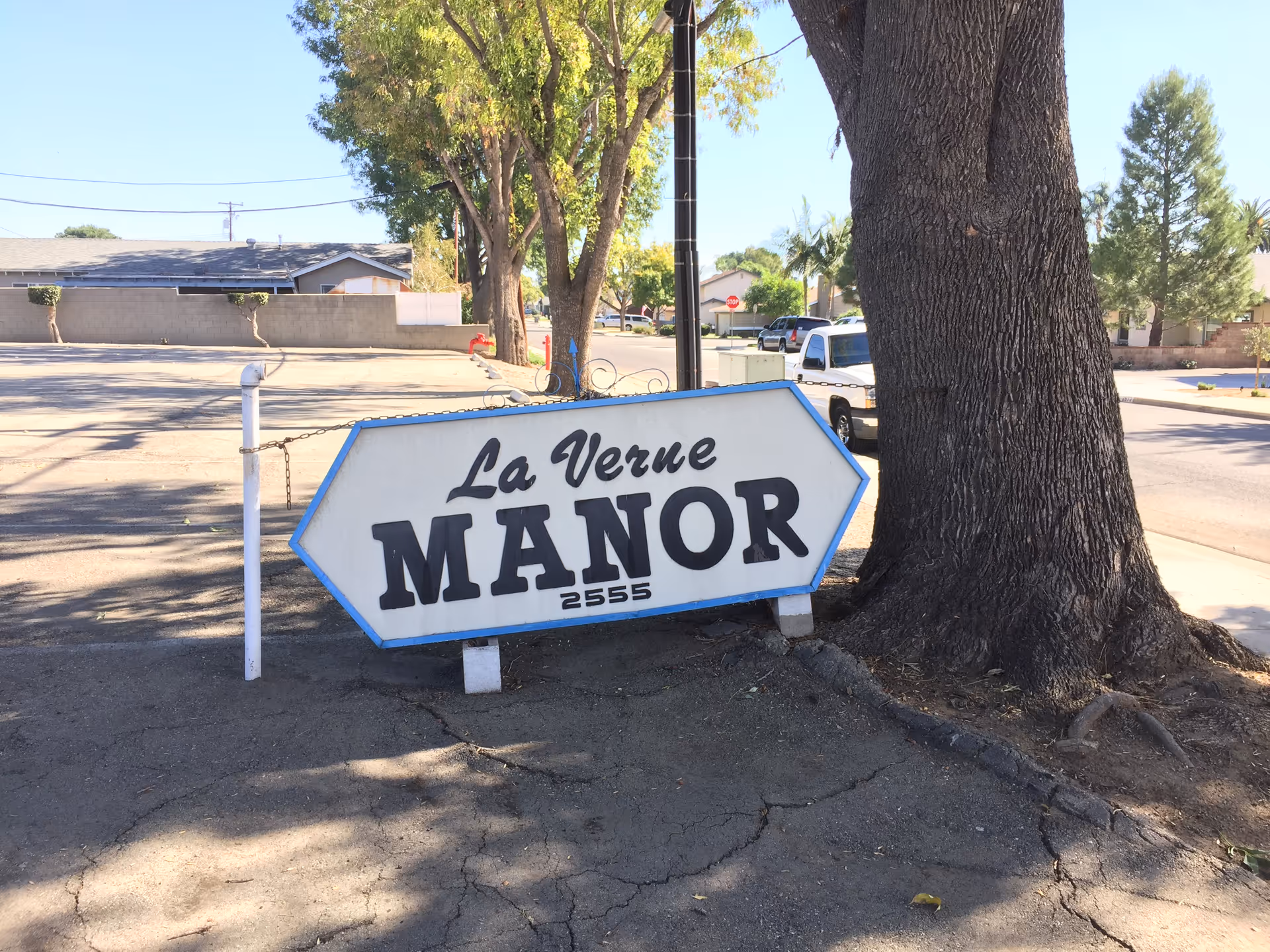 La Verne Manor sign by a large tree along a street.