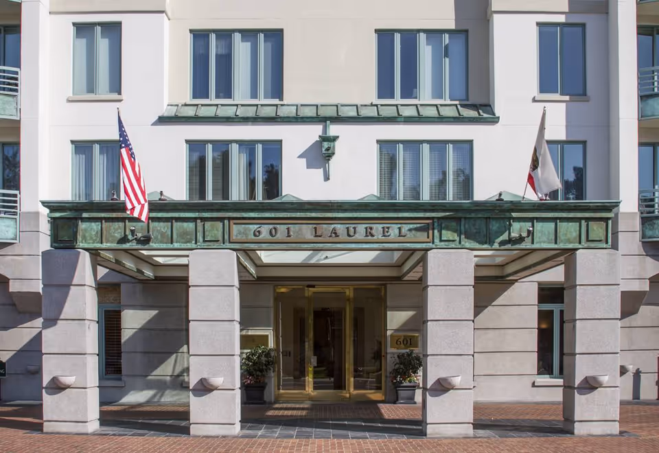 Front entrance of The Stratford senior living with glass doors, flags, and stone columns.