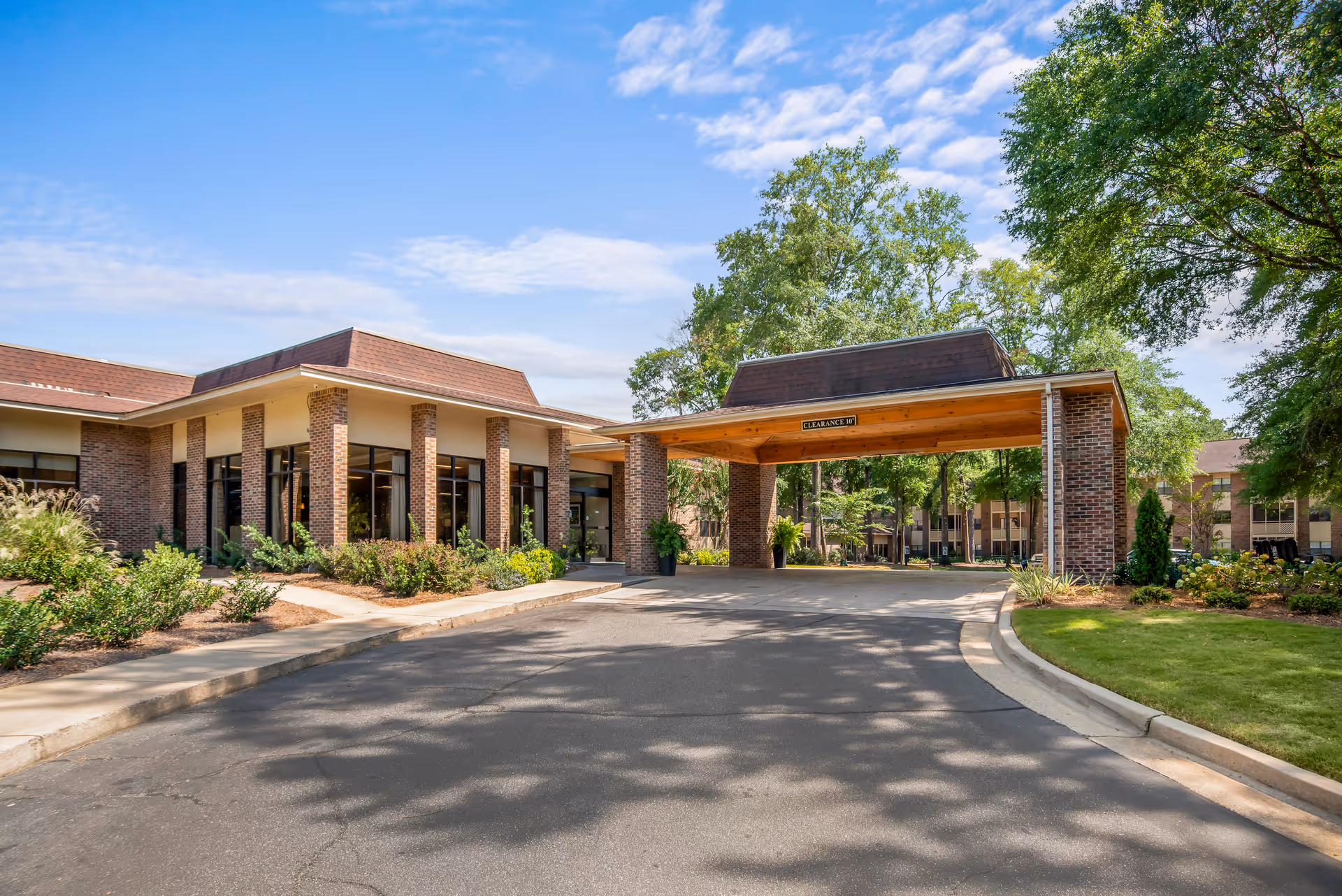 Covenant Woods facility entrance with brick columns and a covered driveway under a blue sky.