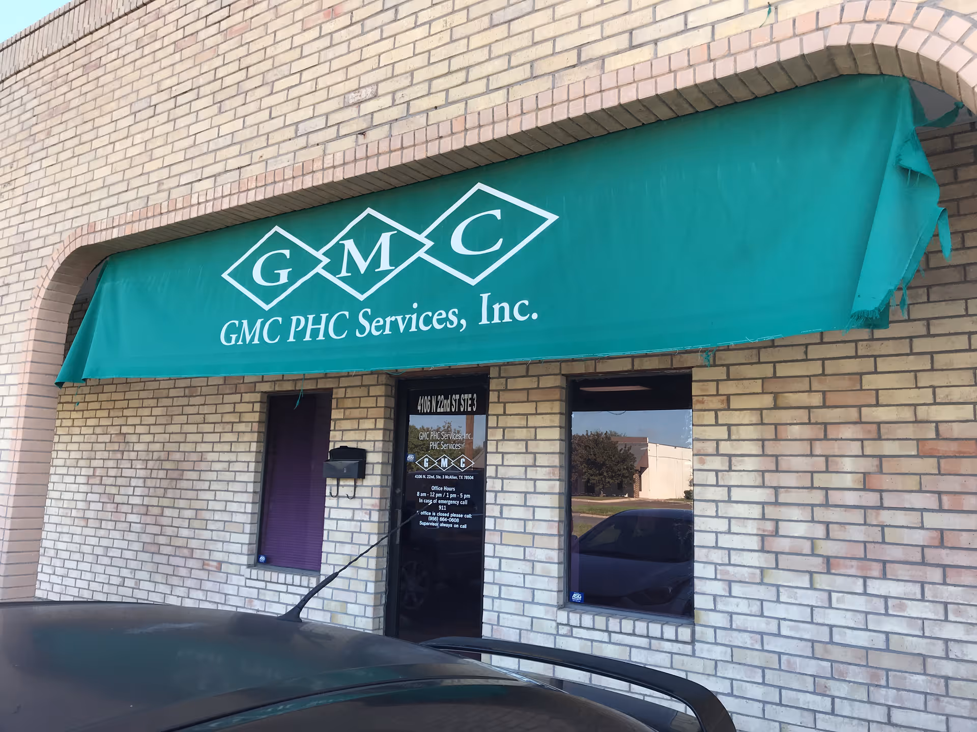 Green GMC PHC Services awning over brick building storefront entrance.
