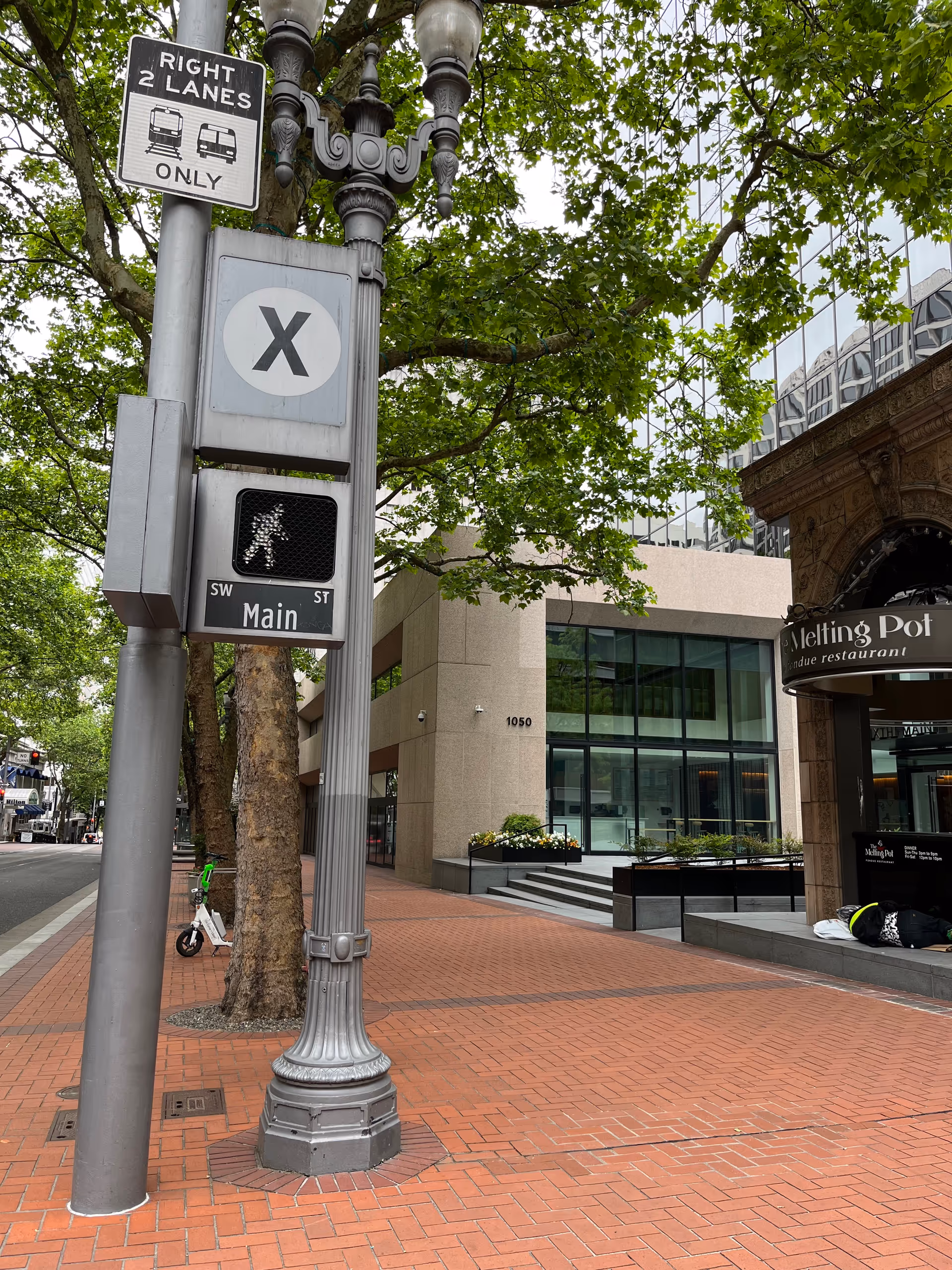 Urban street corner featuring a lamppost, street signs, and a storefront.