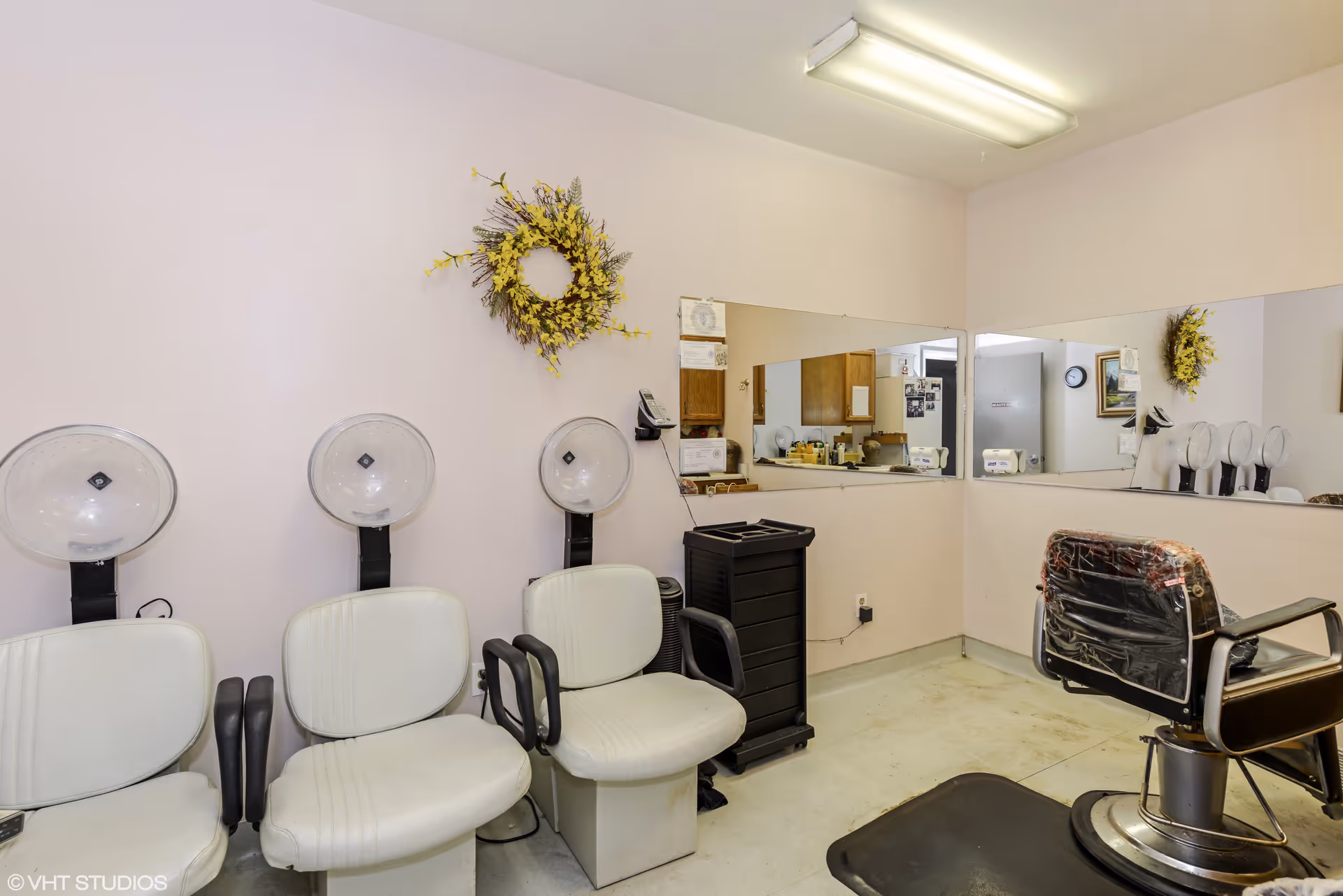 A senior living facility hair salon with white chairs and wall-mounted dryers.