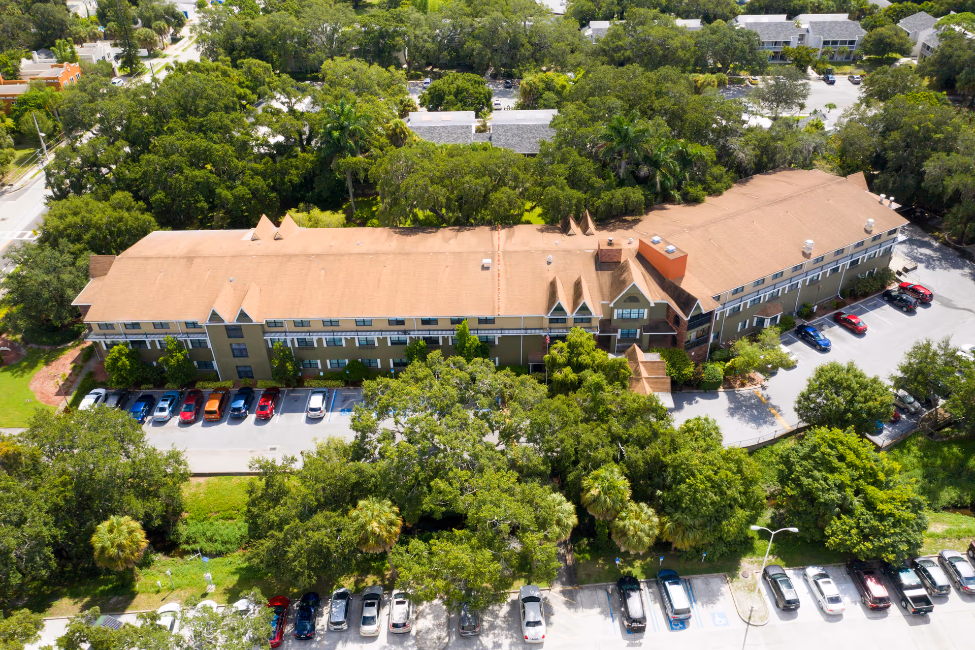 Aerial view of Brookdale Sarasota Midtown exterior building with parking lots and trees.