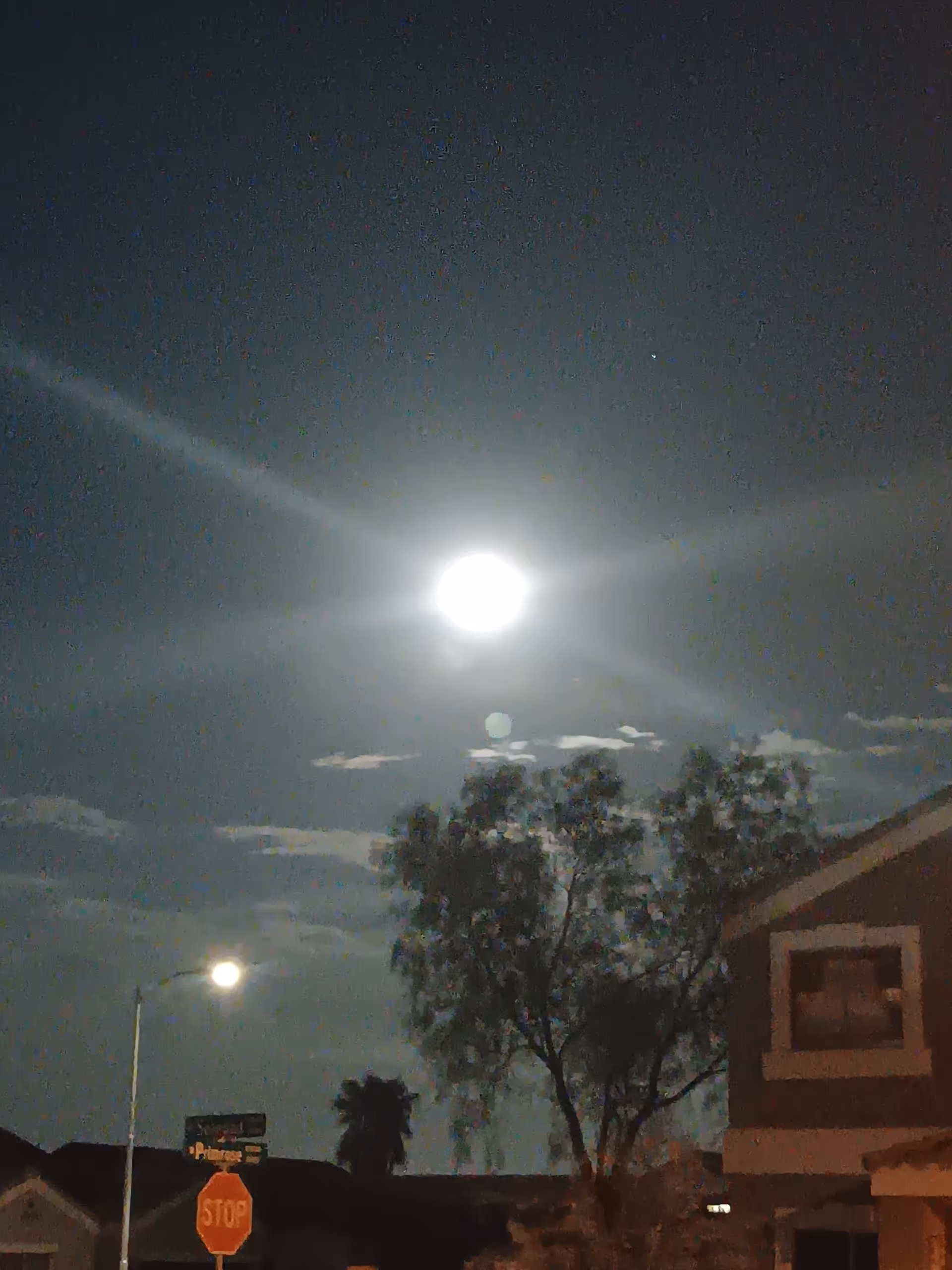 Night exterior of a building with a bright moon, streetlight, and stop sign.