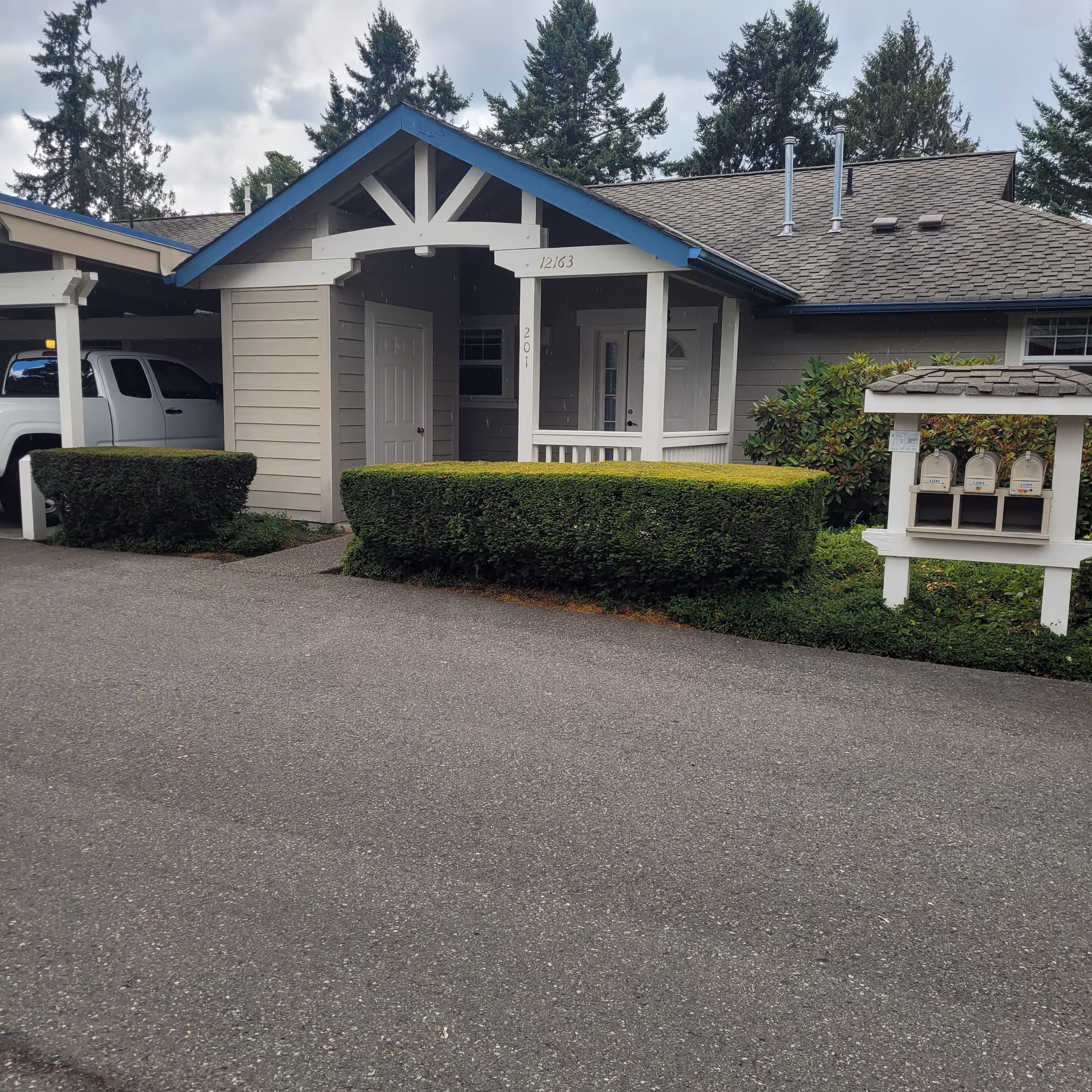 A senior living facility entrance with a small porch, hedges, and a driveway.