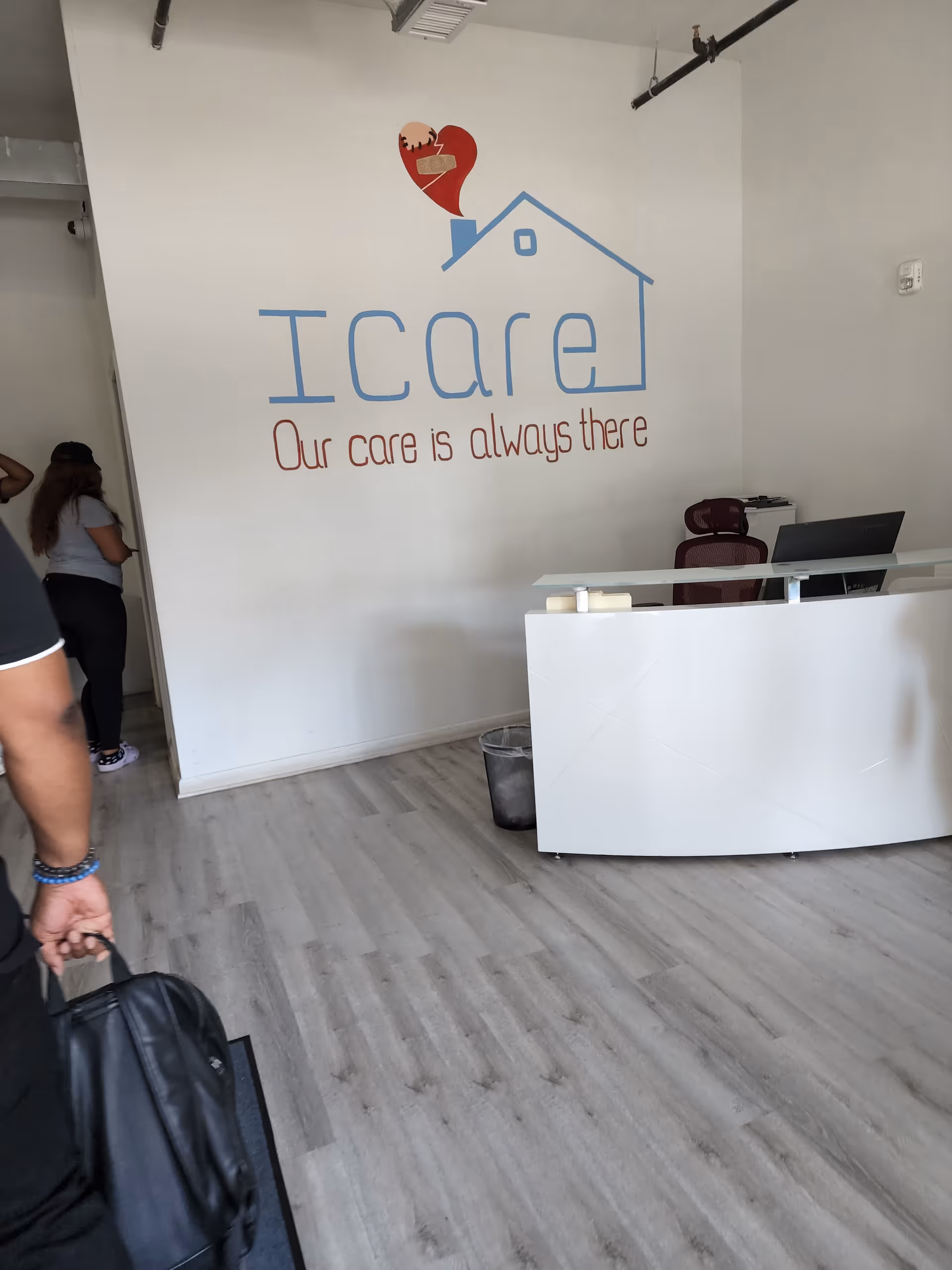 Reception area with ICare logo on wall and a curved white desk.