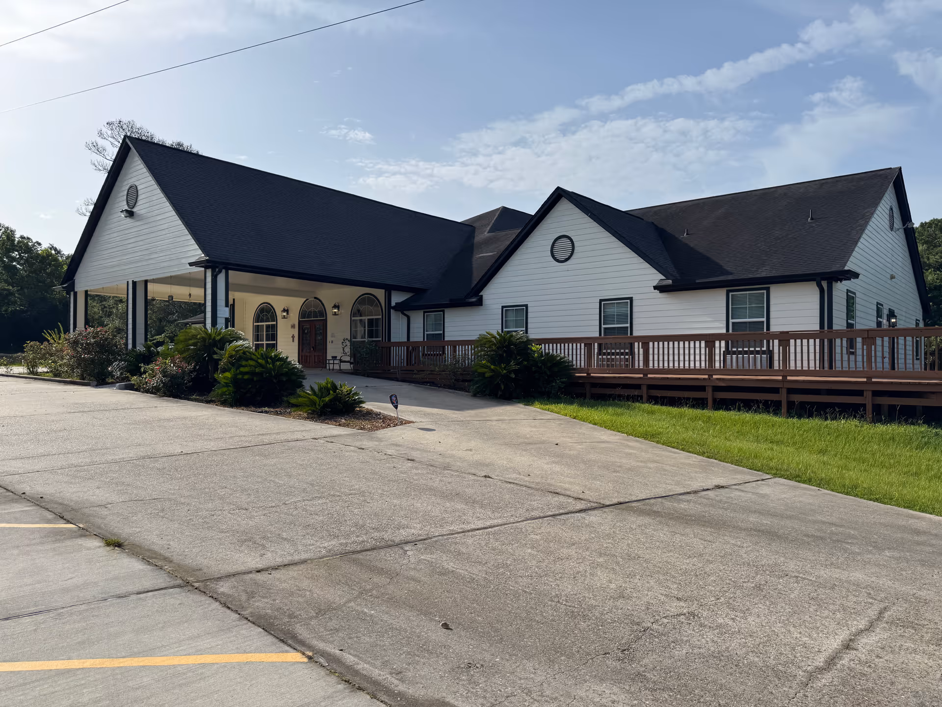 Exterior view of A Village Home senior living facility, white building with dark roof and ramp.