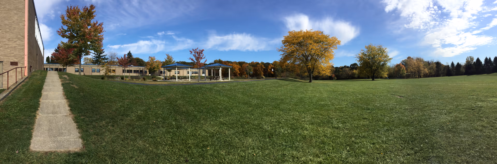 Wide exterior view of a senior living campus with green lawn, trees, and buildings.