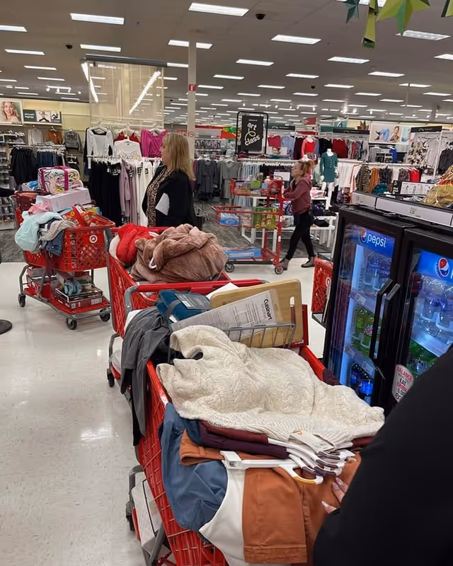 Indoor store aisle with clothing racks, shopping carts, and a Pepsi fridge.