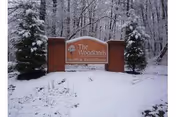 Snow covers the wooded grounds around a sign for The Woodlands Health And Rehab Center.