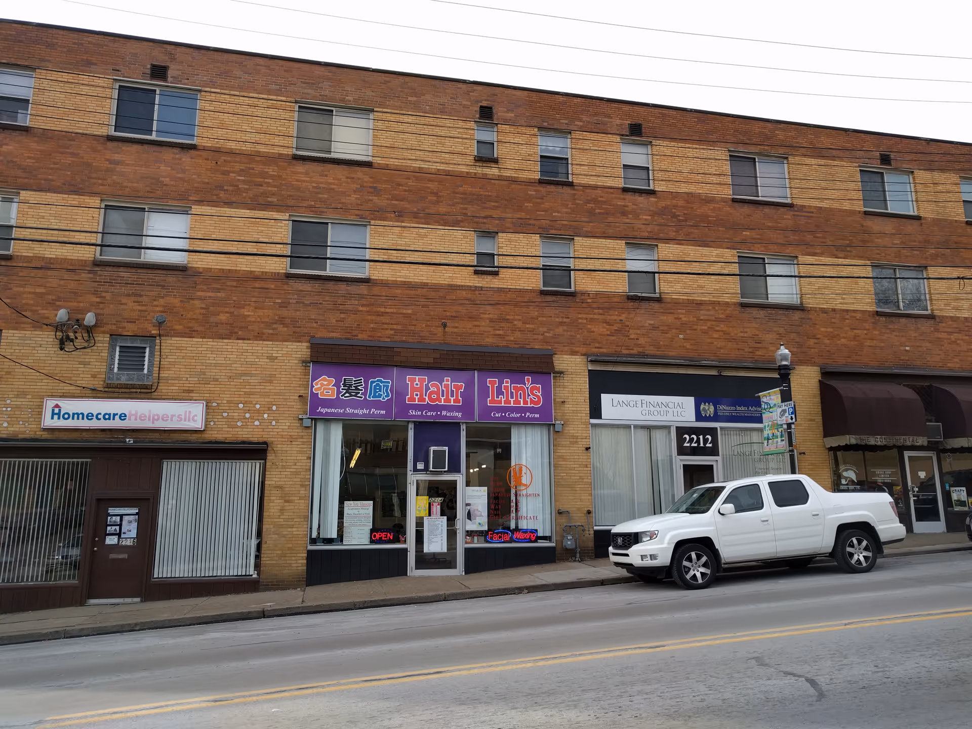 Brick storefronts line a city street, including Homecare Helpers LLC and a hair salon.