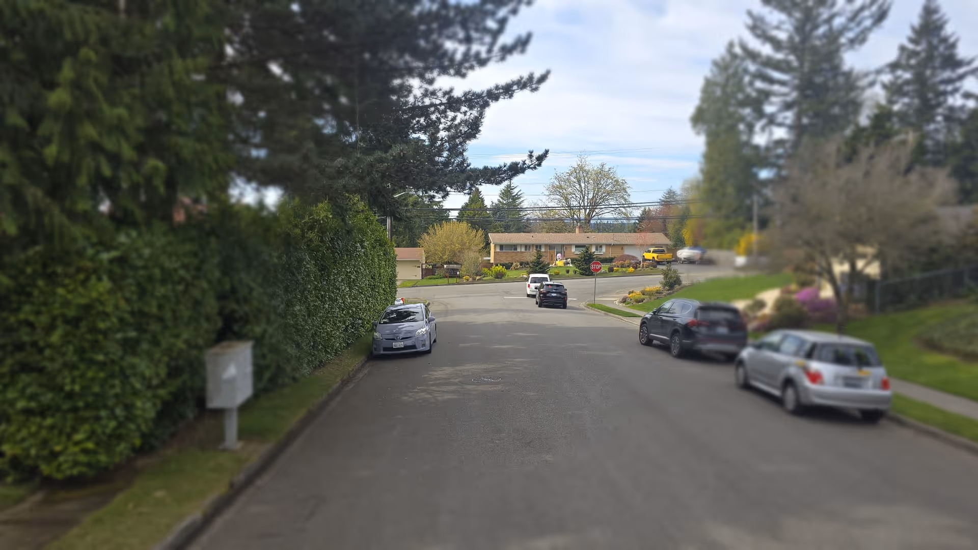 Exterior view of a single-story senior living home along a residential street with parked cars