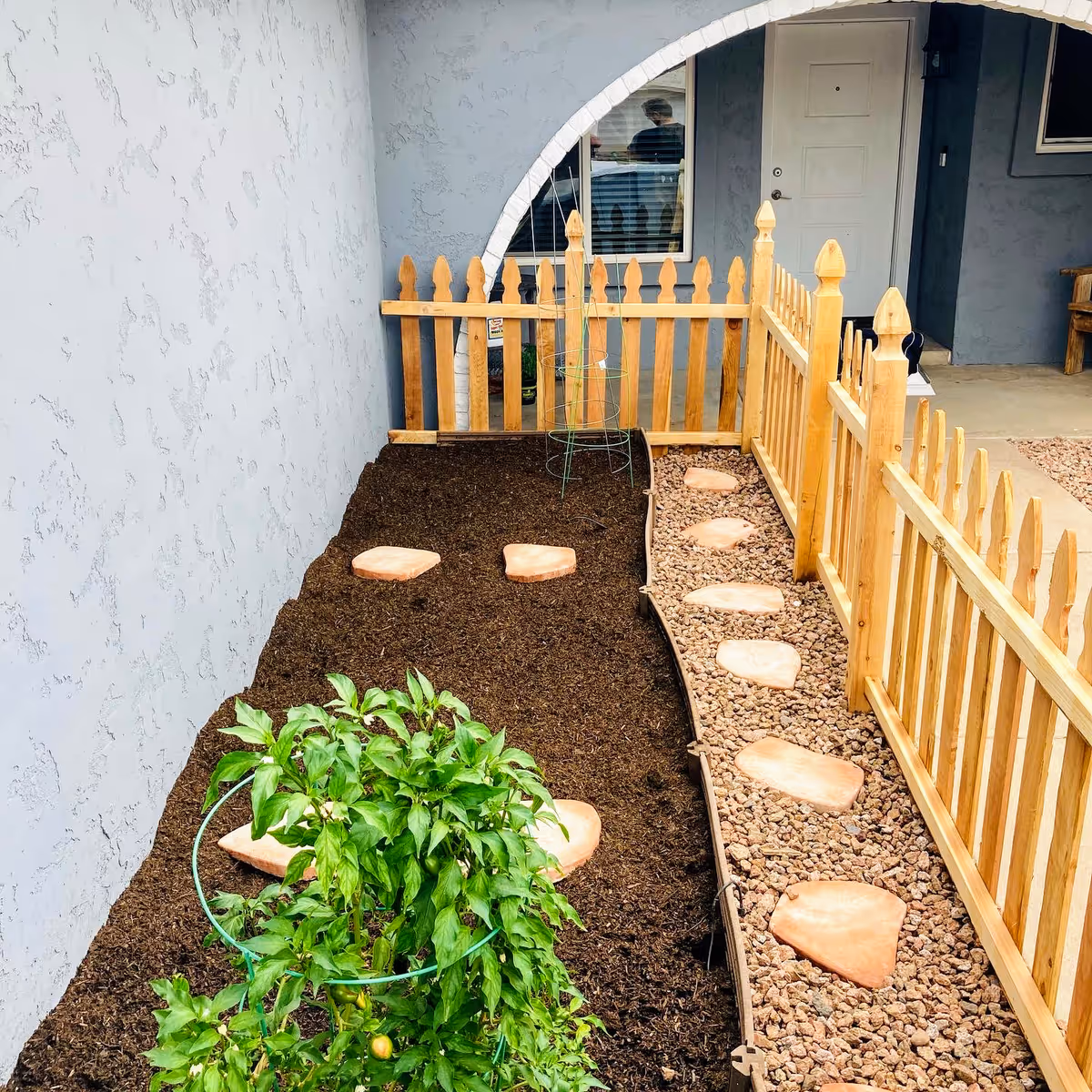 Outdoor courtyard at Bella Amore Assisted Living with a wooden fence and stepping stones.