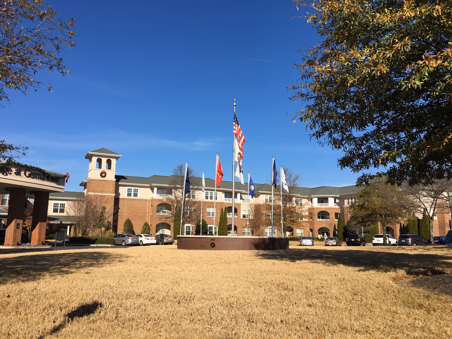 Exterior view of The Village at Germantown showing flags, brick facade, and parked cars.