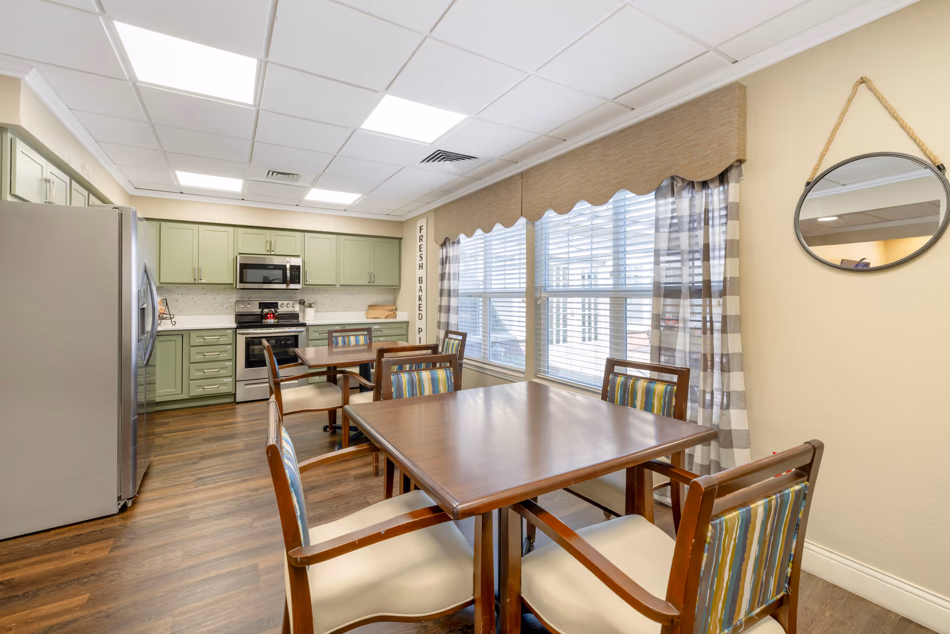 Bright dining area with wooden table and chairs beside a mint-green kitchen.