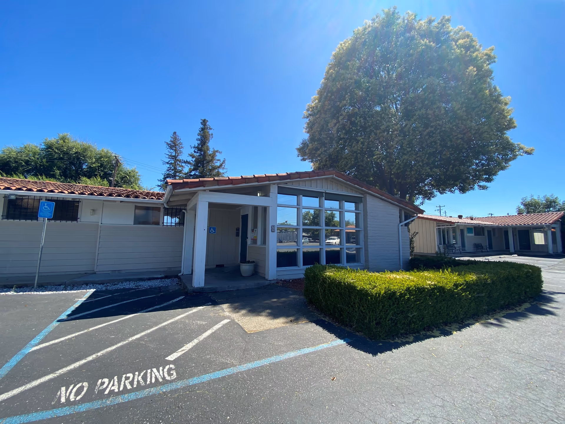 Single-story facility exterior with glass-front entrance, handicap sign, and parking.