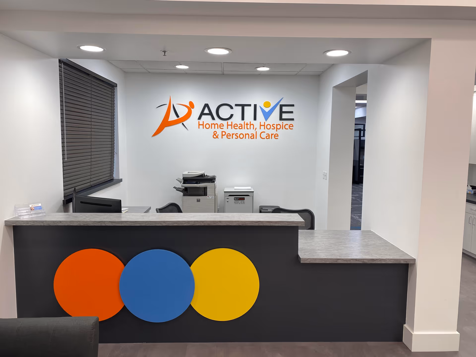 Reception area with Active Home Health logo behind a desk and three colorful circles.