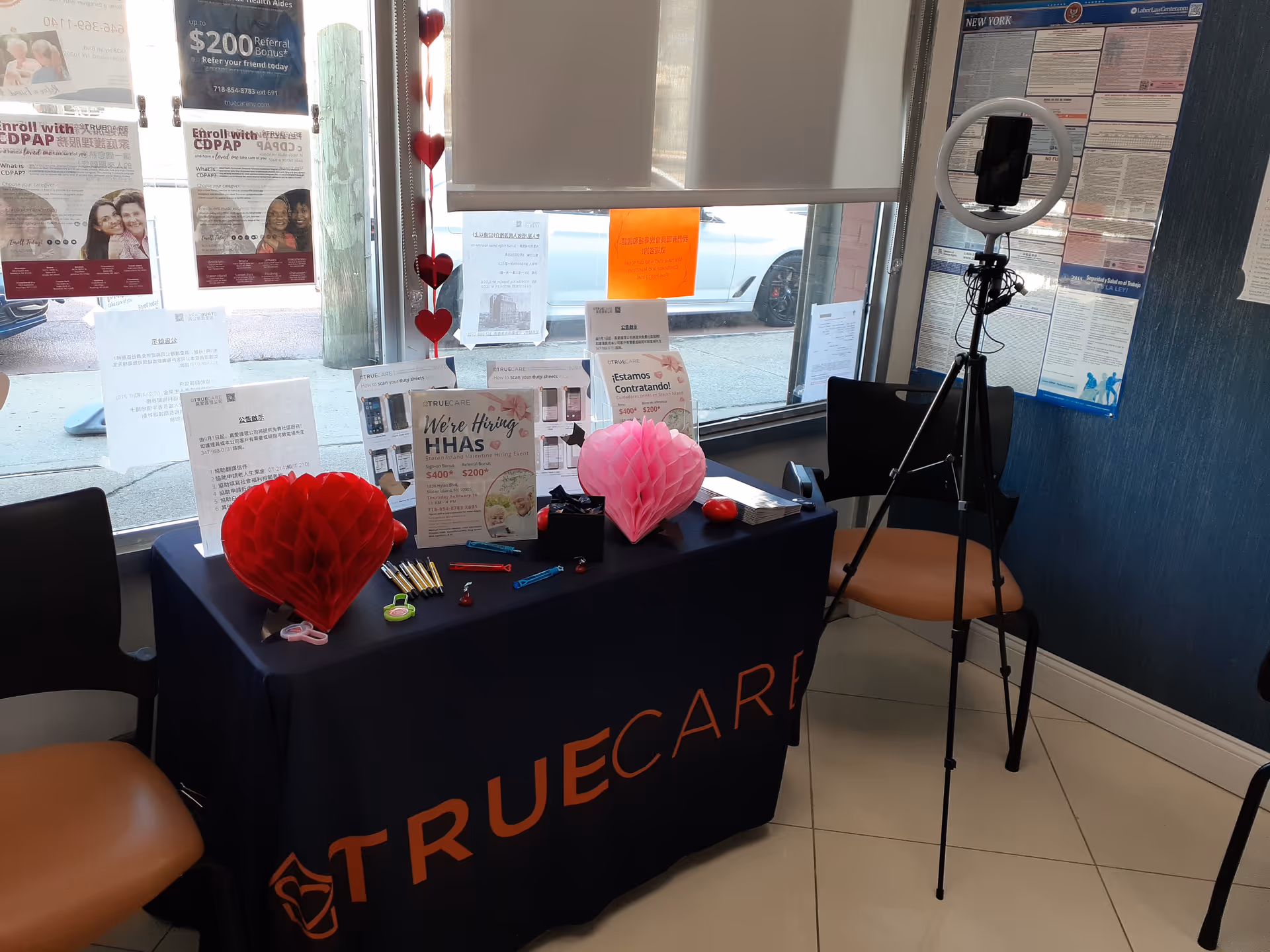 Reception desk with TrueCare promotional materials, a ring light, and seating in a small office lobby.