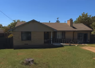 Single-story brick house with a front porch and grassy yard; no people visible.