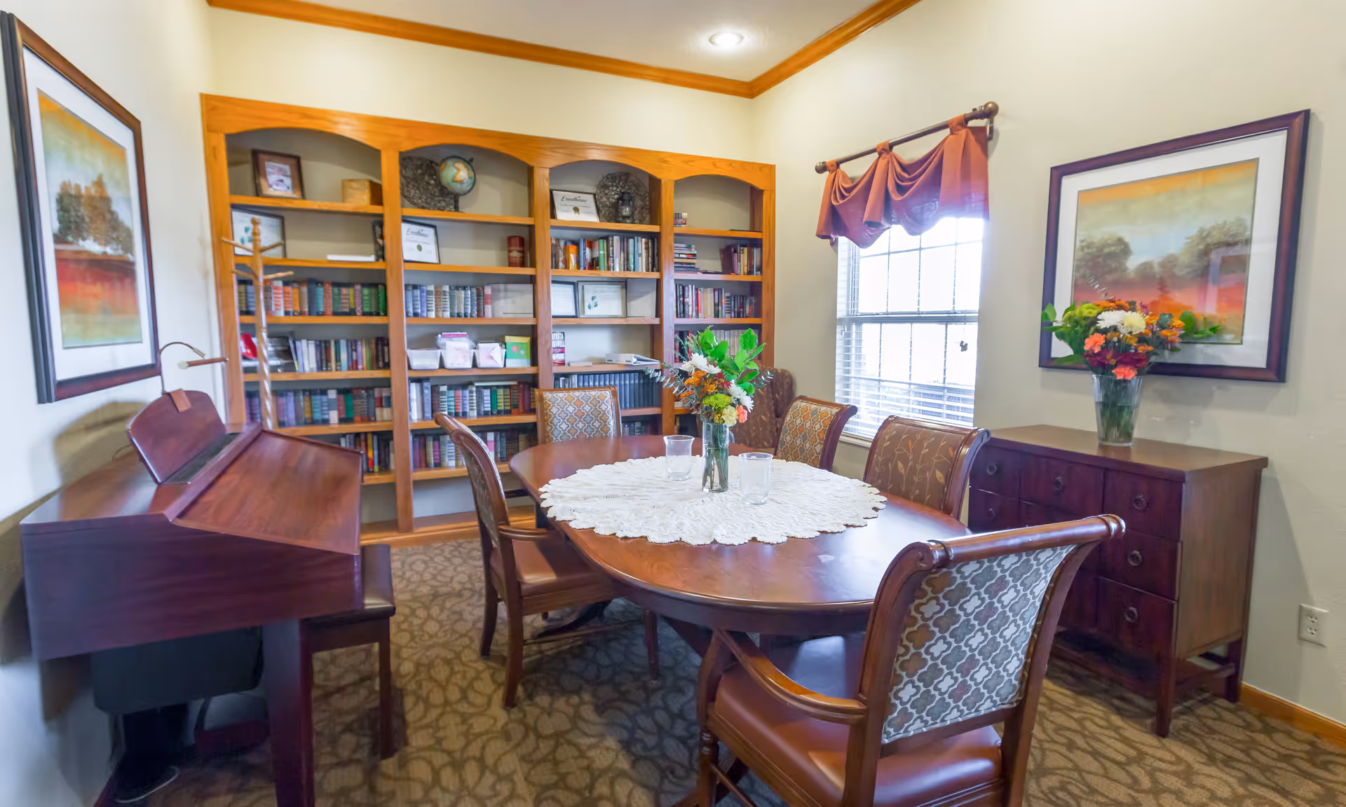 Round wooden dining table with chairs in a library-style dining room.