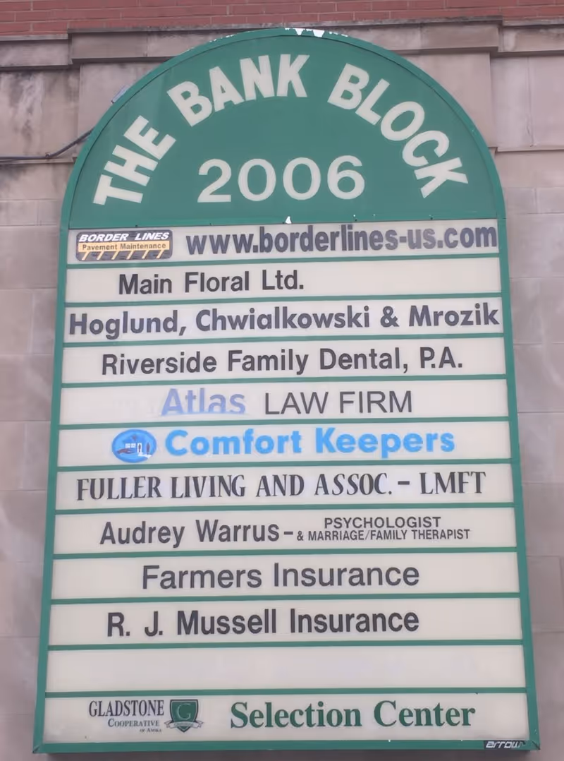 Green arched sign on building exterior listing multiple businesses including Comfort Keepers.