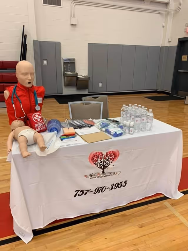 Medical training table with a dummy mannequin, supplies, water bottles, and Heart Harmony branding.