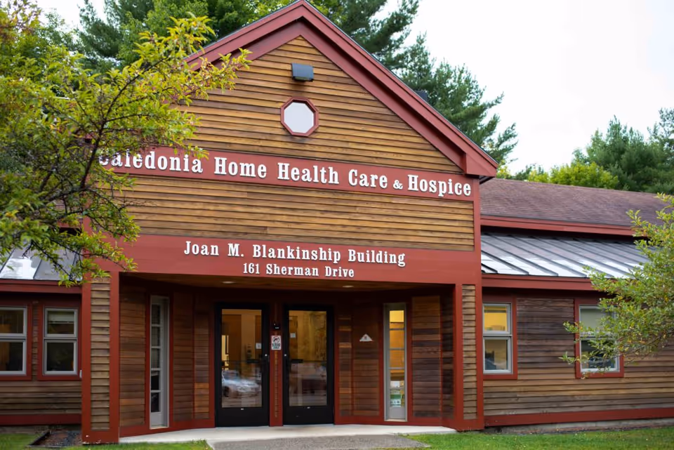 Exterior view of a wooden building with red trim and care signage.