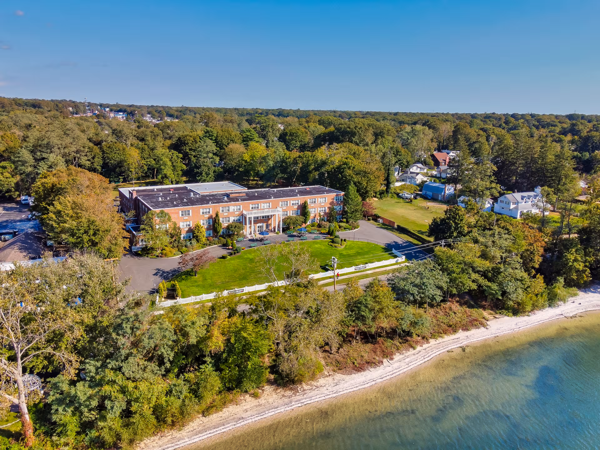 Aerial view of Amber Court senior living campus along a lakefront with trees.