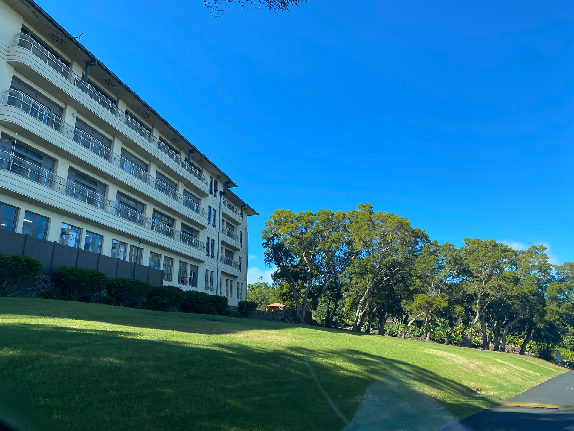 Exterior view of a multi-story senior living building beside a green lawn and trees.