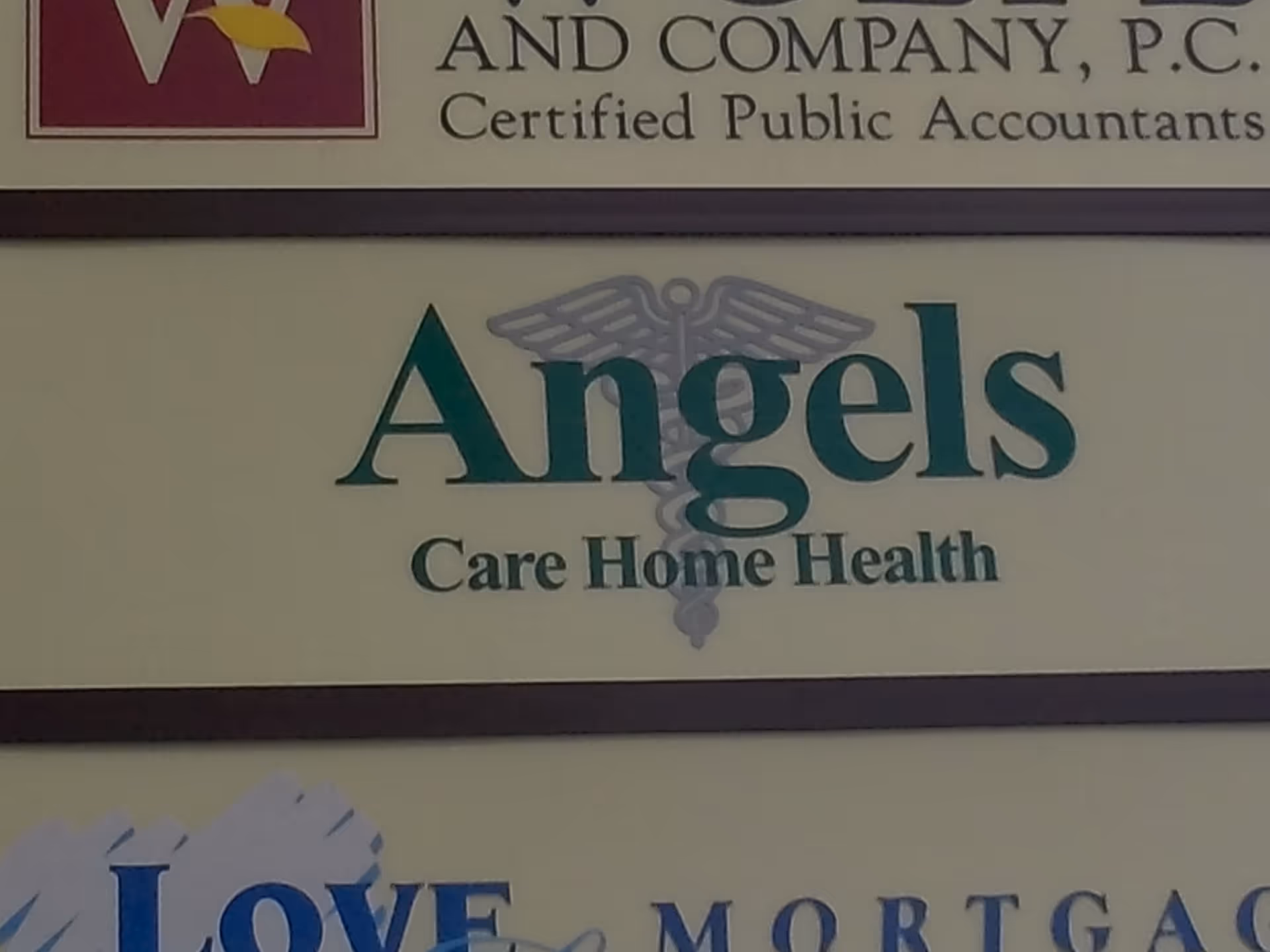 Sign reads Angels Care Home Health on a beige wall outside a building.