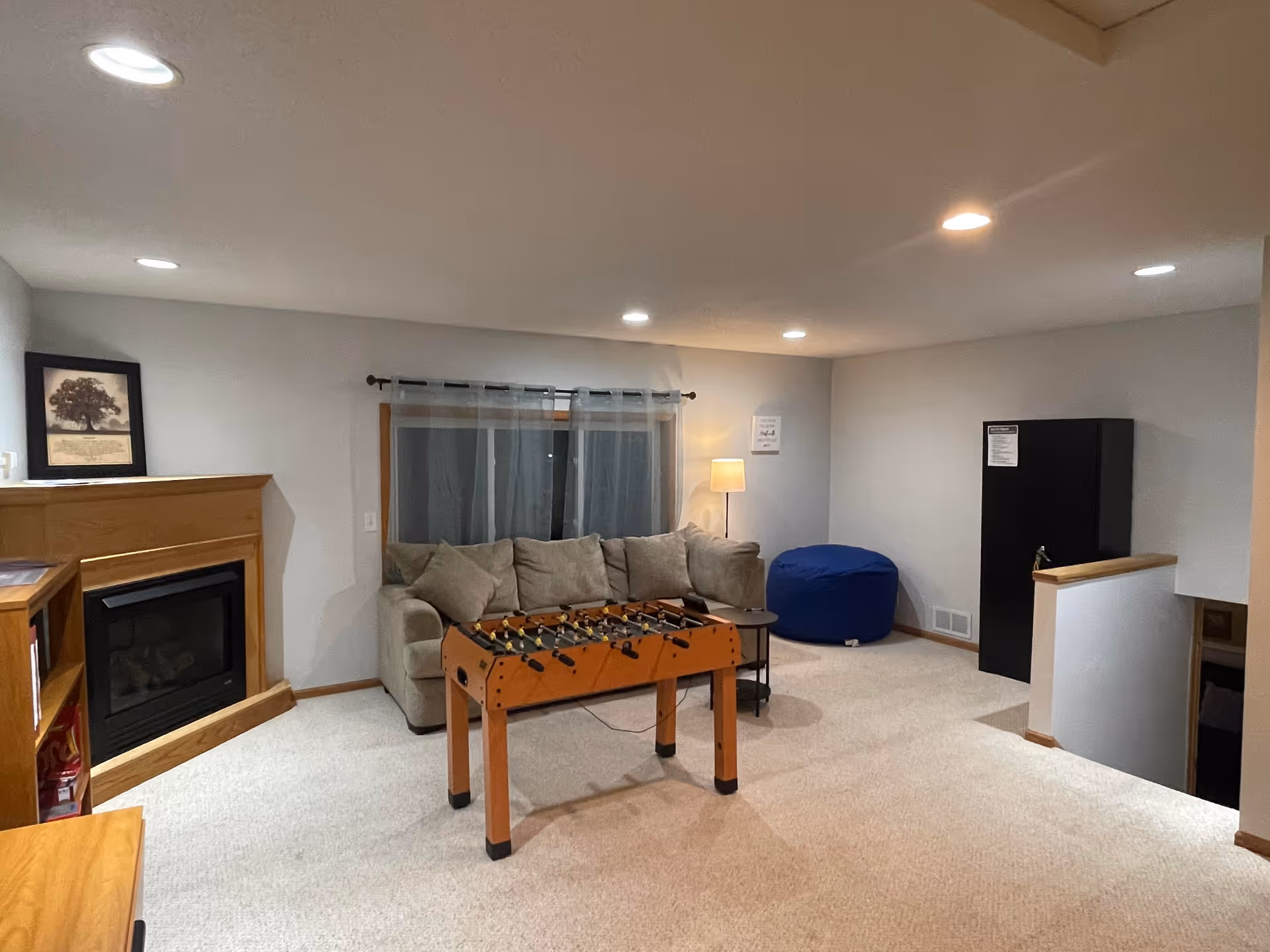 Basement living area with sofa, foosball table, fireplace, and bean bag chair.