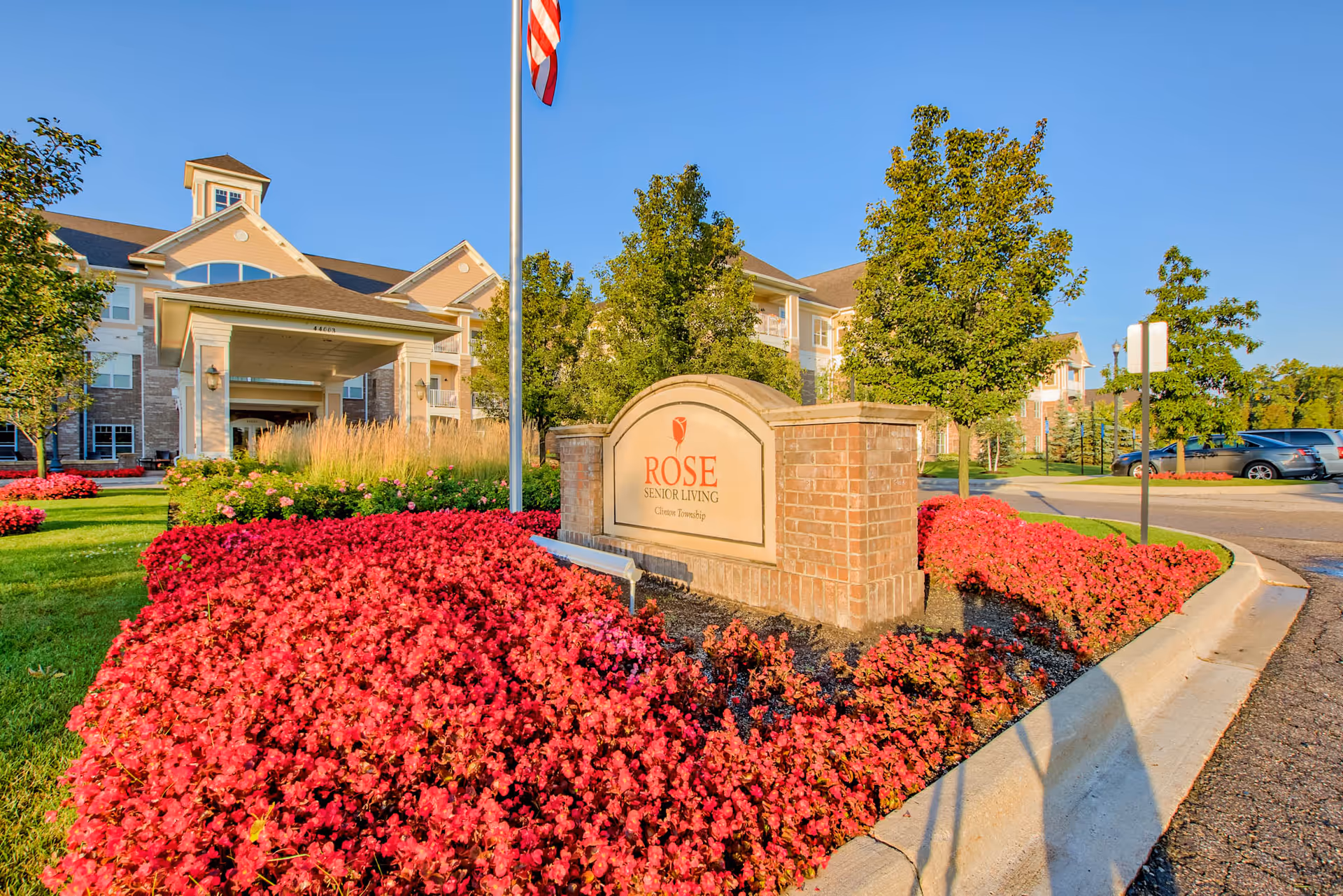 Exterior view of Rose Senior Living Clinton Township with a sign and landscaped entrance.