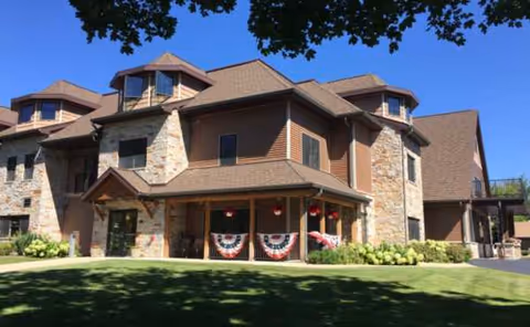 Sherwood Lodge Assisted Living exterior with stone walls and manicured lawn.