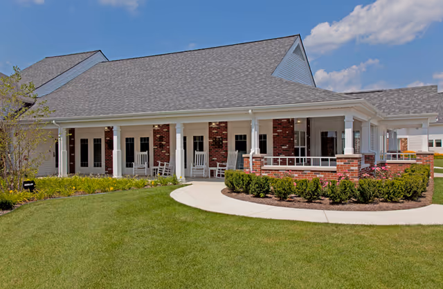 Exterior view of Medilodge of Monroe with a covered porch and rocking chairs.