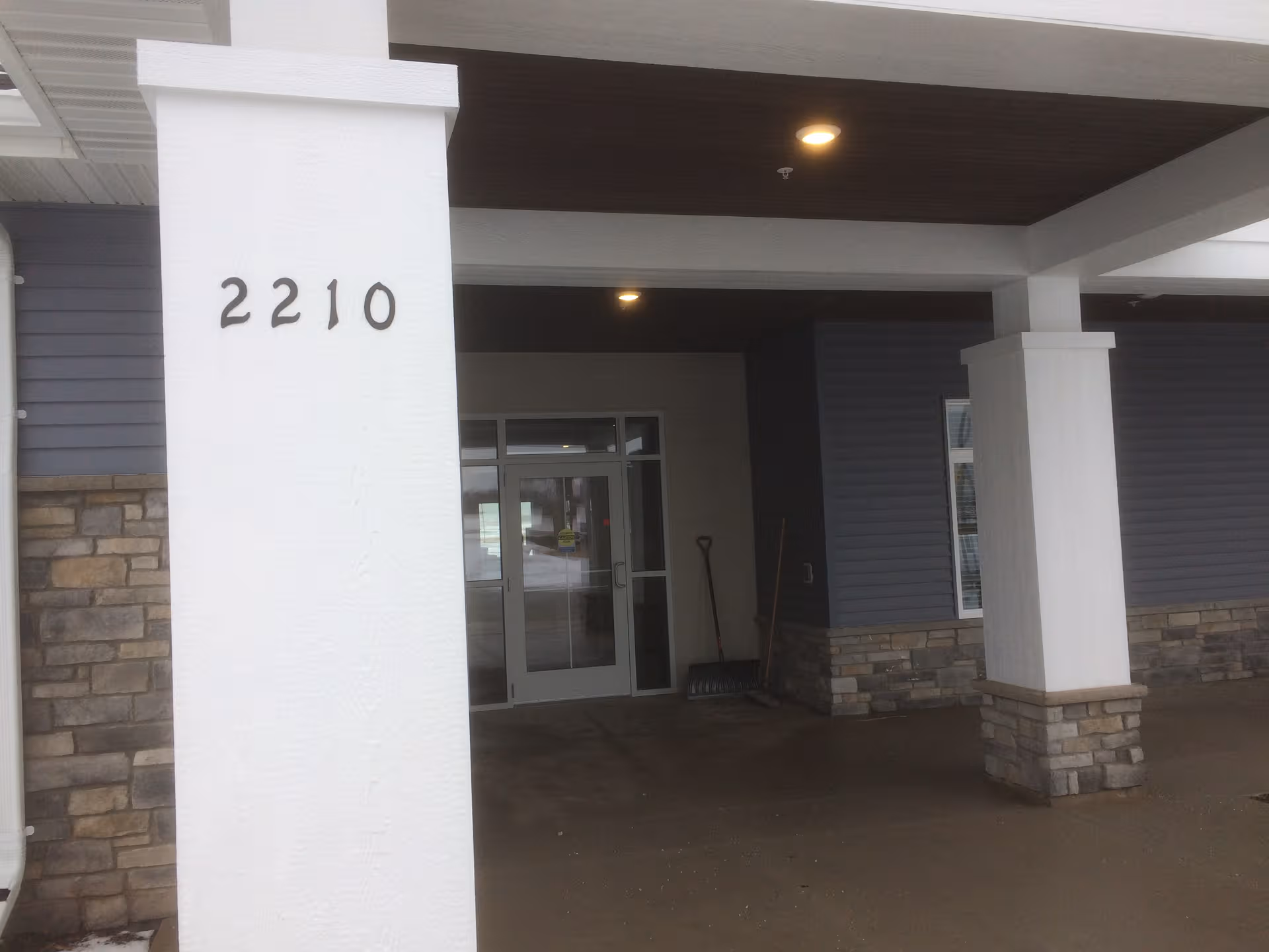 Front entrance of a modern assisted living building with white columns and 2210 address visible.