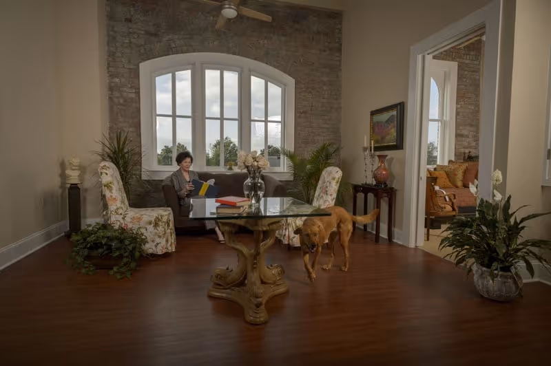 Cozy living room in Belleville senior facility with resident reading near a dog.