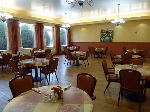 Cozy dining room with round tables, red chairs, and large windows.